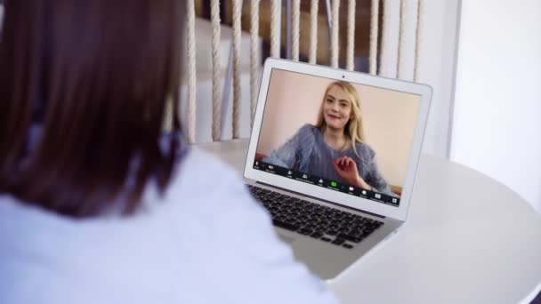Νεαρή ευτυχισμένη ξανθιά γυναίκα μιλάει σε βιντεοκλήση με φίλο χρησιμοποιώντας φορητό υπολογιστή στο σπίτι κουζίνα — Αρχείο Βίντεο
