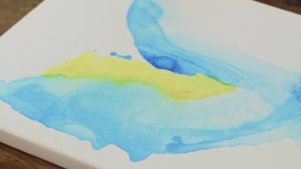 Fluide Art. Peinture abstraite bleue et jaune. Gros plan de l'artiste féminine utilise pulvérisation d'eau pour mélanger des peintures jaunes et bleues — Video