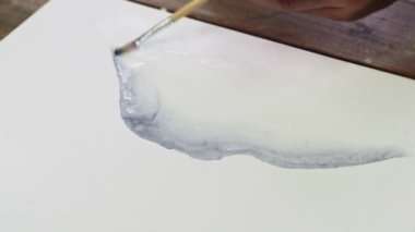 Erkek ressamın yakın çekimi soyut bir resim çizer, ıslak tuvale birkaç damla siyah boya döker ve boya fırçasıyla onu dağıtır.