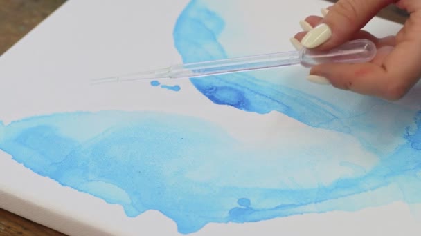 Arte fluido. Pintura colorida abstracta. Primer plano de la artista femenina vierte el agua de la pipeta a la lona con la imagen abstracta azul — Vídeos de Stock