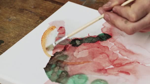 Ovanifrån av konstnären målar en abstrakt bild, han använder pensel på våt duk för att distribuera en orange färg — Stockvideo