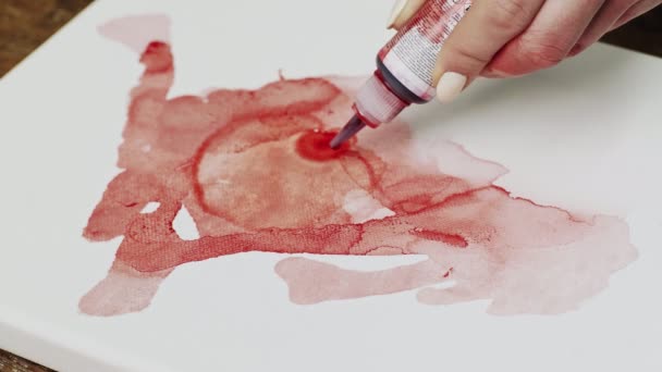 Gros plan de l'artiste peint un tableau abstrait, elle verse quelques gouttes de peinture rouge au milieu de la toile humide — Video