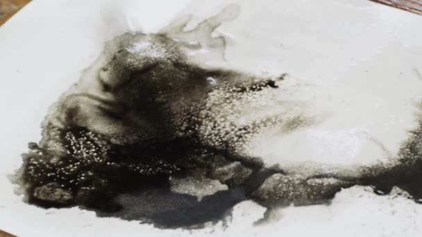 Κοντινό πλάνο του καλλιτέχνη ζωγραφίζει μια αφηρημένη εικόνα χρησιμοποιεί στεγνωτήριο για να μετακινήσετε μαύρη μπογιά σε βρεγμένο καμβά — Αρχείο Βίντεο
