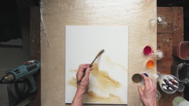 Arte fluido. Pintura colorida abstracta. Vista superior de artista masculino utiliza pincel para pintar un abstracto formas marrones sobre lienzo húmedo — Vídeo de stock