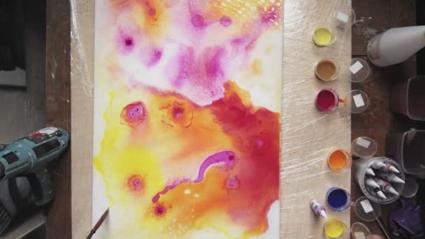 Arte Fluida. Pintura colorida abstrata. Vista superior do artista masculino usa pincel para pintar uma forma abstrata na tela molhada — Vídeo de Stock