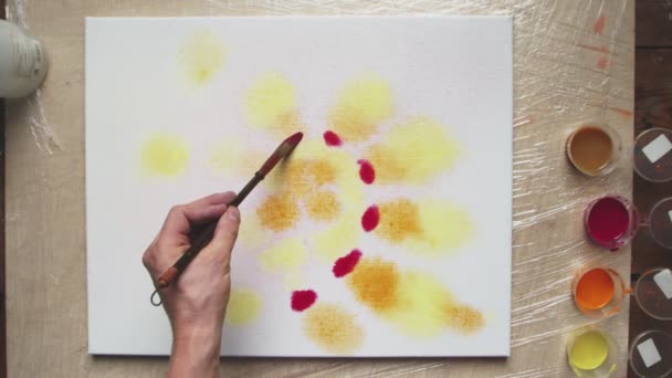 Widok z góry męskich farb artystycznych Pastel tie barwnika lub Pastel wirować obraz. Używa Spray Bottle do dodawania wody na płótnie. Podnosi płótno i obraca je, by przenosić farby.. — Wideo stockowe