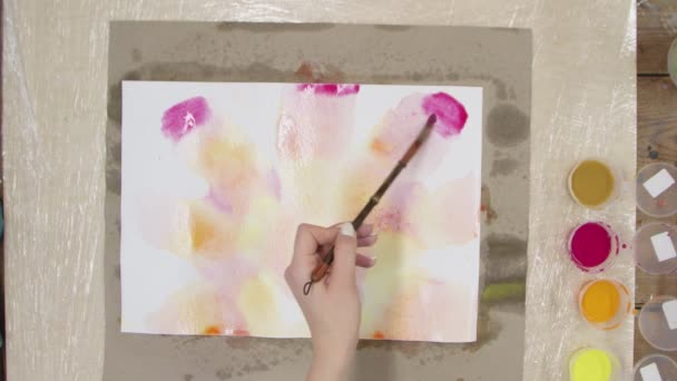 Kadın ressamın üst görüntüsü Pastel kravat boyasını sarı, kırmızı ve turuncu boyalarla ıslak tuvale boyuyor. Sıvı Sanat. — Stok video