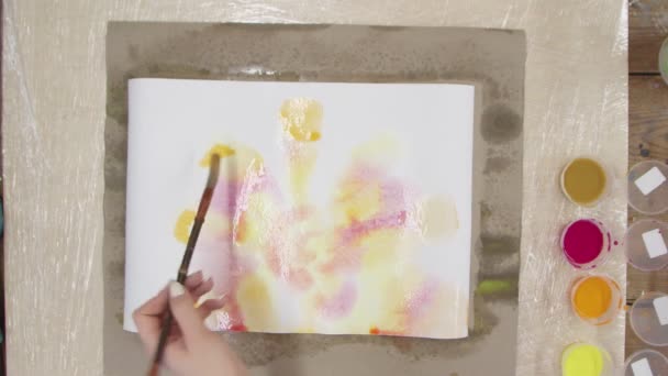 Верхний вид женщины-художника рисует картину пастельного галстука с желтыми и оранжевыми красками на мокром холсте. Fluid Art. — стоковое видео