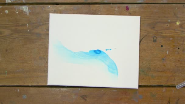 Ovanifrån av människan konstnär målar vacker abstrakt bild, häller han blå färg från röret på våt duk använder torktumlare för att flytta en blå färg och torr — Stockvideo