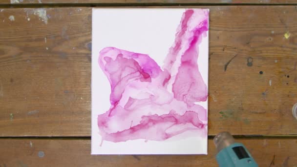 Жидкое искусство. Абстрактная розовая картина. Вид сверху на женщину-художницу использует сушилку для перемещения розовой краски и сушки ее новой розовой картины — стоковое видео