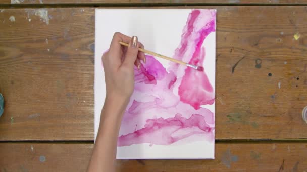 Arte Fluida. Pintura rosa abstrata. Vista superior da artista feminina pinta uma forma rosa abstrata na tela molhada — Vídeo de Stock