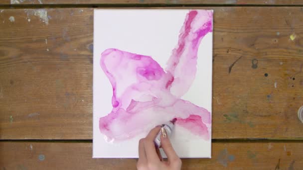 Vista superior da mulher artista pinta bela imagem abstrata, ela derrama rosa do tubo na tela molhada e usa pincel para distribuí-lo — Vídeo de Stock
