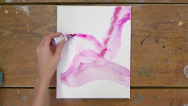 Kadın ressamın üst görüntüsü soyut pembe bir tablo çiziyor, ıslak tuvale pembe boya döküyor. — Stok video