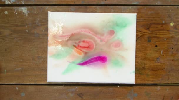 Vista superior do artista pinta uma imagem abstrata, ele usa tinta roxa na tela molhada e usa secador para movê-lo e secar — Vídeo de Stock