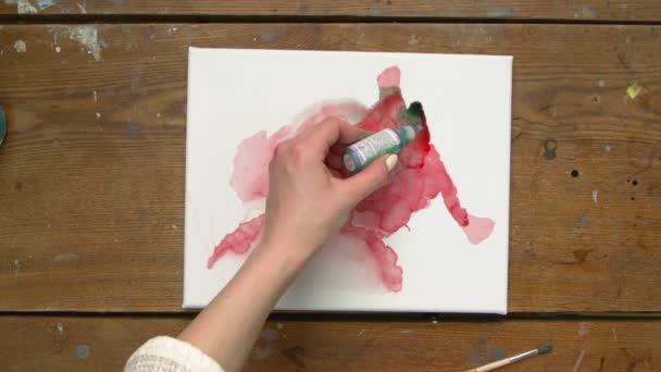 Top view két művész festeni egy absztrakt képet: az egyik tölt néhány csepp zöld fájdalom nedves vászon és a második használ ecsetet, hogy terjessze azt — Stock videók