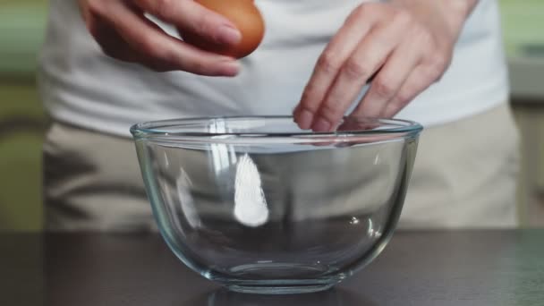 Розбиваємо яйце в скляну миску. Свіже органічне яйце падає в миску . — стокове відео