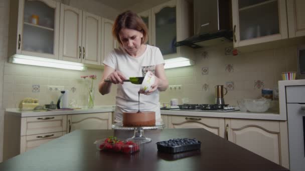 Hausfrau gießt Schokoladenglasur als Sahnehäubchen auf den Kuchen — Stockvideo