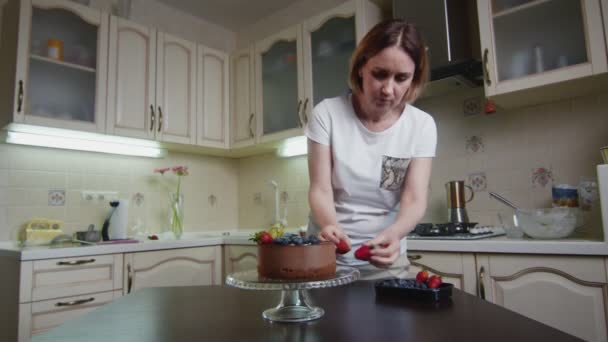 Hausfrau dekoriert den Schokoladenkuchen mit Beeren — Stockvideo