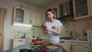 Ev kadını çikolatalı pastayı böğürtlenlerle süslemeyi bitirdi ve fotoğrafını çekti.