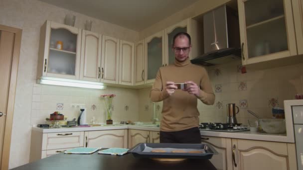 Männlicher Koch fotografiert Lebkuchen auf Tisch in Küche — Stockvideo