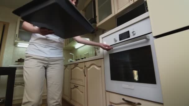 Ama de casa mujer pone bandeja para hornear con galletas de jengibre en el horno — Vídeo de stock