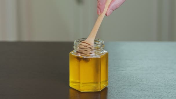 Miele grezzo organico liquido in vaso di vetro con paletta di legno. — Video Stock