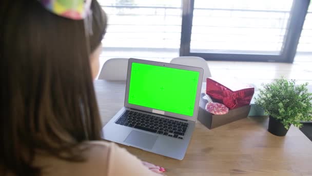 Mujer celebrando su cumpleaños a través de una videollamada fiesta virtual. Mujer mira el monitor con pantalla verde — Vídeos de Stock