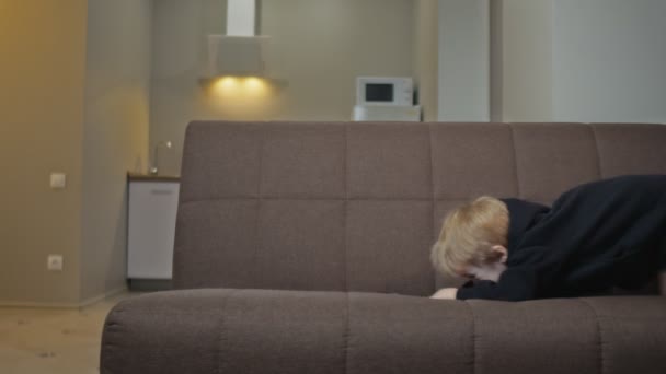 Kleiner Junge hat Spaß zu Hause. Kleiner Junge spielt auf Couch — Stockvideo