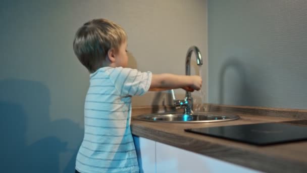 Junge spült Geschirr in der heimischen Küche, Lifestylekonzept. Babywaschbecken an der Spüle — Stockvideo