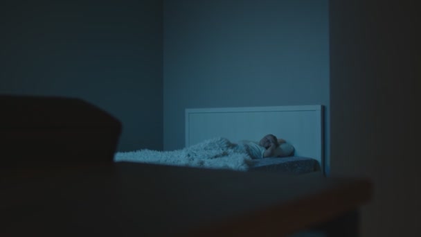 Menino pleeps na cama no quarto escuro à noite — Vídeo de Stock
