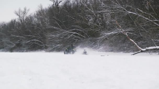 越野车四驱车在雪地上漂流.冬天，骑四轮驱动自行车的男人会把女人拖在冰冻的河上的雪管上 — 图库视频影像