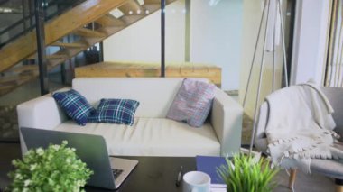 Genç Afrikalı Amerikalı iş adamı ofise geldi ve ofis ofisindeki kanepeye yaslanmış, ofisteki not defterine yazı yazan dizüstü bilgisayar üzerinde çalışmaya başladı.