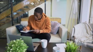 Genç Afro-Amerikan iş adamı serbest çalışan öğrenci defterine bakar ve notlar alır.