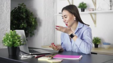 Genç bir kadın iş arkadaşlarıyla görüntülü konuşmak için dizüstü bilgisayar kullanıyor.