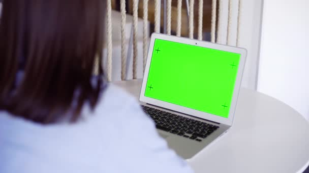Plus sholder vue de la femme travaillant sur ordinateur portable vert écran chromatique au bureau à la maison. Femme regarde l'écran et parle — Video