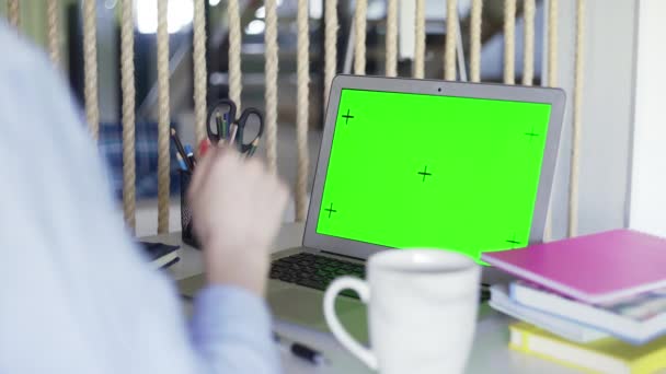 Meer dan sholder uitzicht van de vrouw die werkt op laptop groene scherm chromakey op kantoor. Vrouw kijkt naar het scherm en praat — Stockvideo