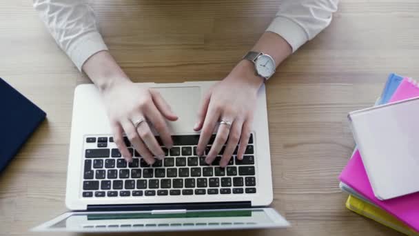 Vista superior de la mujer joven escribiendo en el ordenador portátil. Colocado en escritorio de madera — Vídeo de stock