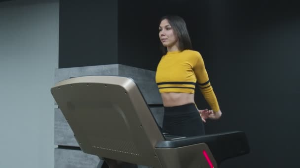 Fitness woman makes exercise to warm up while walks on treadmill in gym — Stock Video