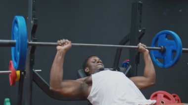 Genç kaslı afro güçlü bir adam halterle ağırlık kaldırıyor..