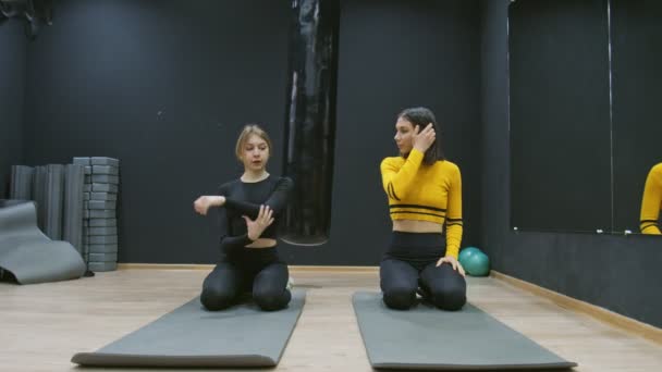 Twee jonge fitnessvrouwen die met de hand en sholders stretchen om zich op te warmen voor de training — Stockvideo