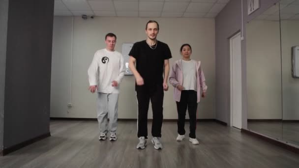 Una donna e due uomini ballano hip hop, una danza contemporanea giovanile in stile libero in uno studio di danza. — Video Stock