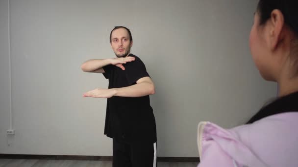 Ung mandlig danselærer viser moderne bevægelser til kvindelig teenager træning i studiet sammen – Stock-video