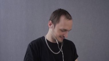 Altın zincirli genç adam telefonda kulaklıkla müzik dinliyor.