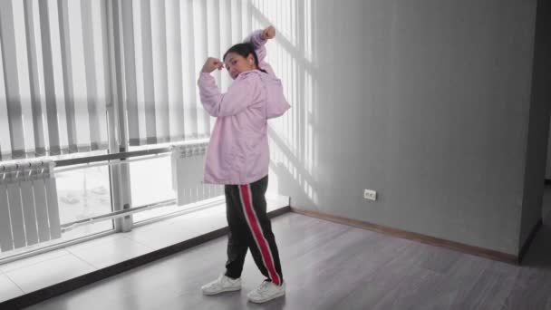 Vonzó és gyönyörű ázsiai nő fejhallgató táncoló hip hop és felébredni stúdióban ablak a háttérben — Stock videók