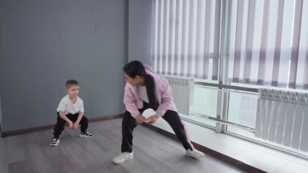El niño hace ejercicio para calentarse y prepararse para la clase de breakdance hip-hop — Vídeo de stock