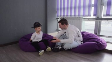 Genç dans öğretmeni, küçük öğrencisine telefonda video gösteriyor.