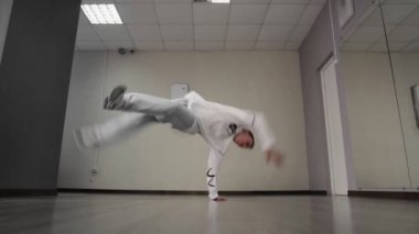 Genç break dansçı stüdyoda hip hop dansı yapıyor. Yakışıklı adam yerde dans hareketleri yapıyor.