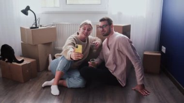 Mutlu çift yeni bir eve taşındıktan sonra rahatlar. Çift yerde oturuyor ve yeni evlerine taşınmalarını kutluyor. Alkol içer ve selfie çeker.