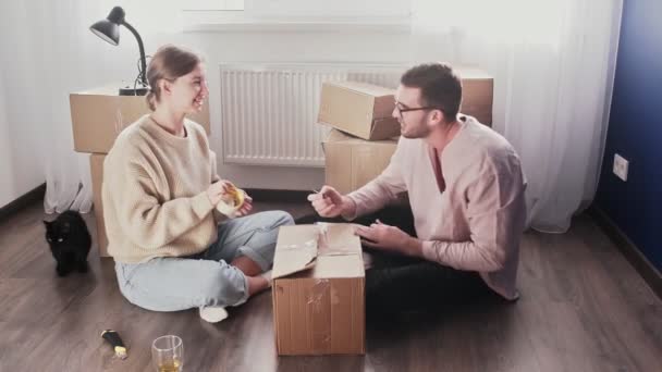 Casal feliz embalando caixas de papelão, prepare-se para sair realocação, família sentada no chão na sala de estar no dia em movimento — Vídeo de Stock