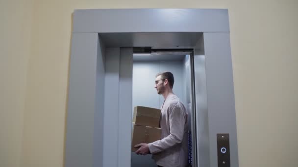 Genç bir çift karton kutularla asansörden çıkıp yeni bir daireye taşınıyor. — Stok video